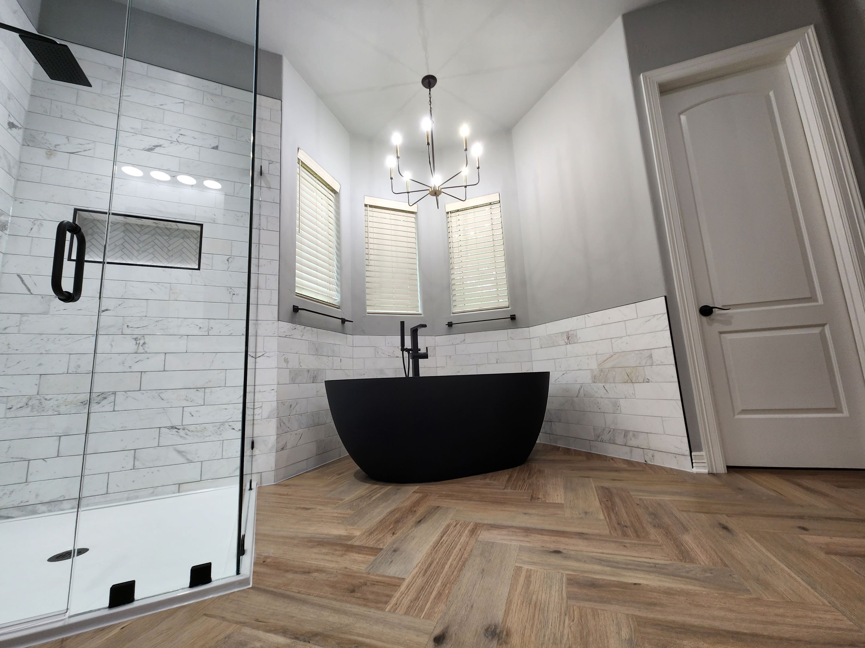 modern sleek san antonio bathroom remodel with free standing black tub and marble tile in shower