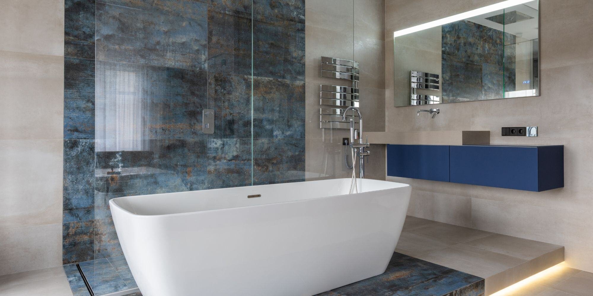 statement tile bathroom with marbled blue bathroom tile, white free standing tub, sleek bathroom vanity, and smart mirror